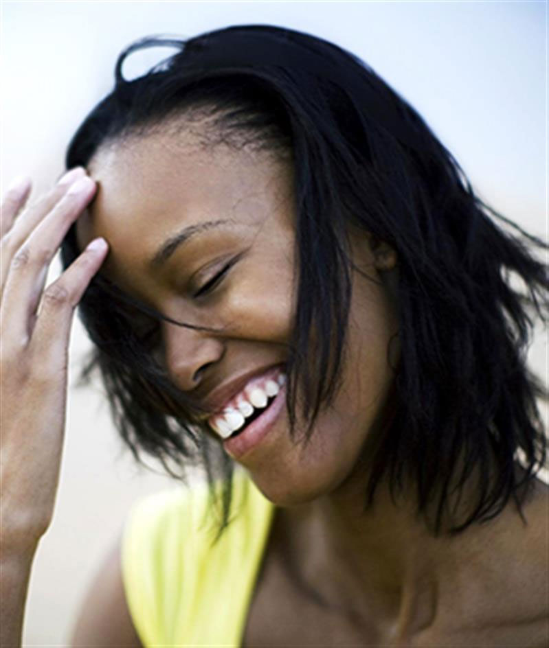 A woman smiling and brushing back her dark hair-happiness