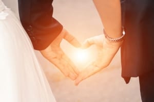 A couple making a heart symbol with their hands- Couples Retreats