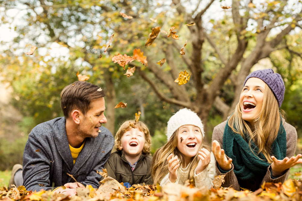 Image of a family of four playing in leaves-Family Retreat