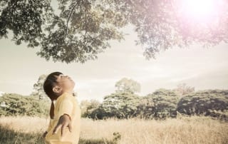 Girl standing under a tree with her arms wide open-inner child