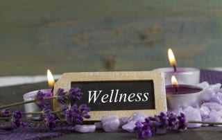 A small sign amidst candles that says Wellness-Wellness Retreat