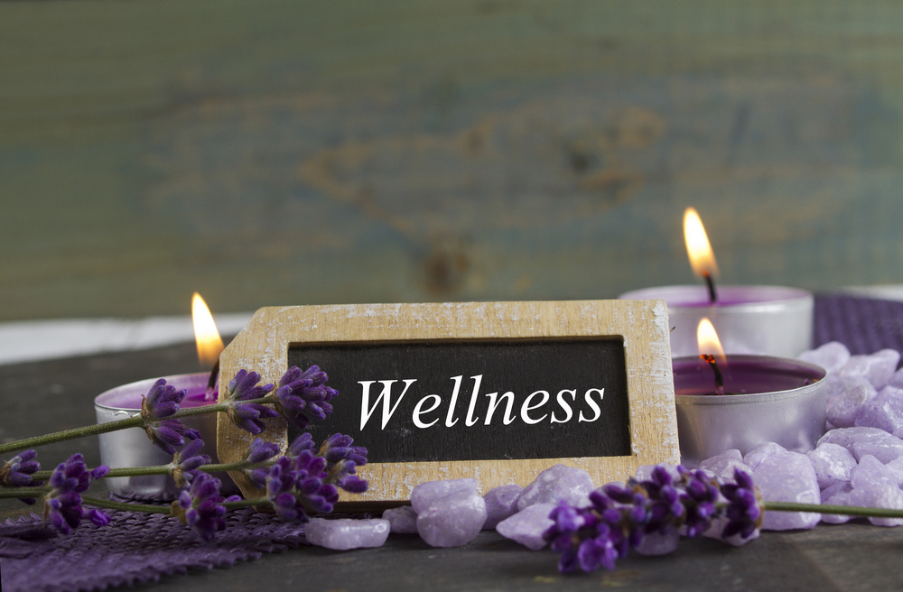 A small sign amidst candles that says Wellness-Wellness Retreat