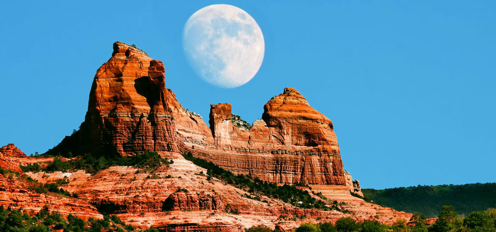 Full moon rising over red rock formations in Sedona, Arizona for spiritual retreats.