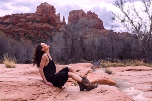 Woman on red rocks sitting and looking up at sky-Sedona-Healing
