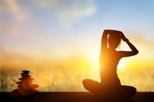 Woman sitting in yoga pose at sunrise-Yoga Retreats