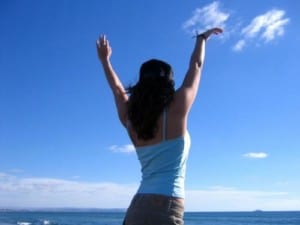 Young woman with arms up on the air looking at clouds-inner peace