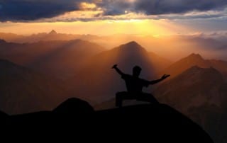 a man doing tai chi on top of a mountain at sunrise