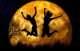 Two silhouettes jumping up onfront of a full moon at night-Women's retreats