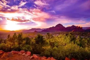 Vibrant sunrise over Sedona red rock vortex sites with purple and orange sky.