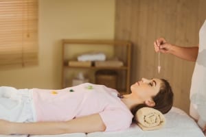 Crystal pendulum hovering a woman's head- Healing retreat