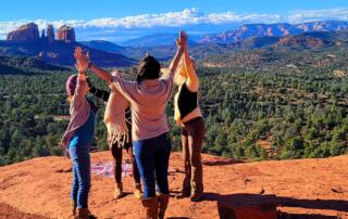 group grasping hands on the redrocks of sedona healing retreat