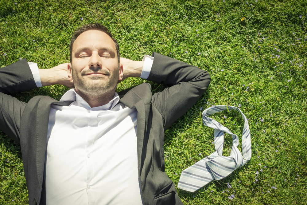 Man in a suit with a tie lying in the grass
