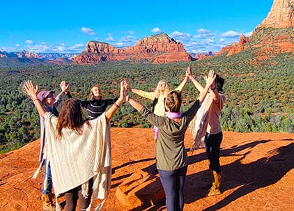 spirit-quest-sedona-path-to-transformation-team spiritquest transformation team on red rocks holding hands