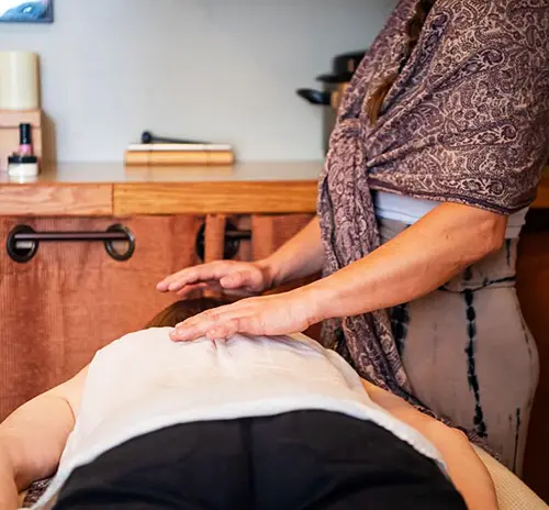 SpiritQuest-treatment-hands-on-1042 A healing practitioner's hands placed on a client's shoulder during a private somatic release session at SpiritQuest Sedona