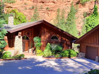 Exterior of the Owl Room Lodging sanctuary with red rock mountains and a clear blue sky.
