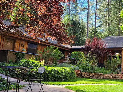 Exterior of the SpiritQuest Sedona lodging sanctuary building with a stone path and lush garden seating.