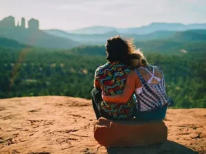 Two people sitting together on a Sedona red rock overlook during a SpiritQuest healing retreat.