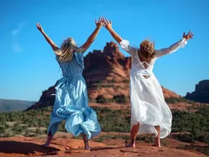 two women jumping in joy on the red rocks during a healing retreat
