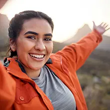 Holly, a spiritquest client, stands with her arms spread with Sedona in the background.
