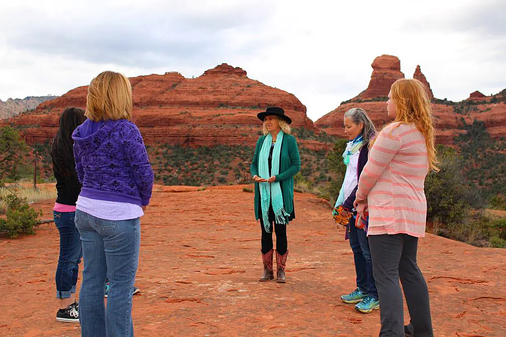 A group of retreat participants standing in a circle during a guided vortex experience on the red rocks of Sedona, Arizona.