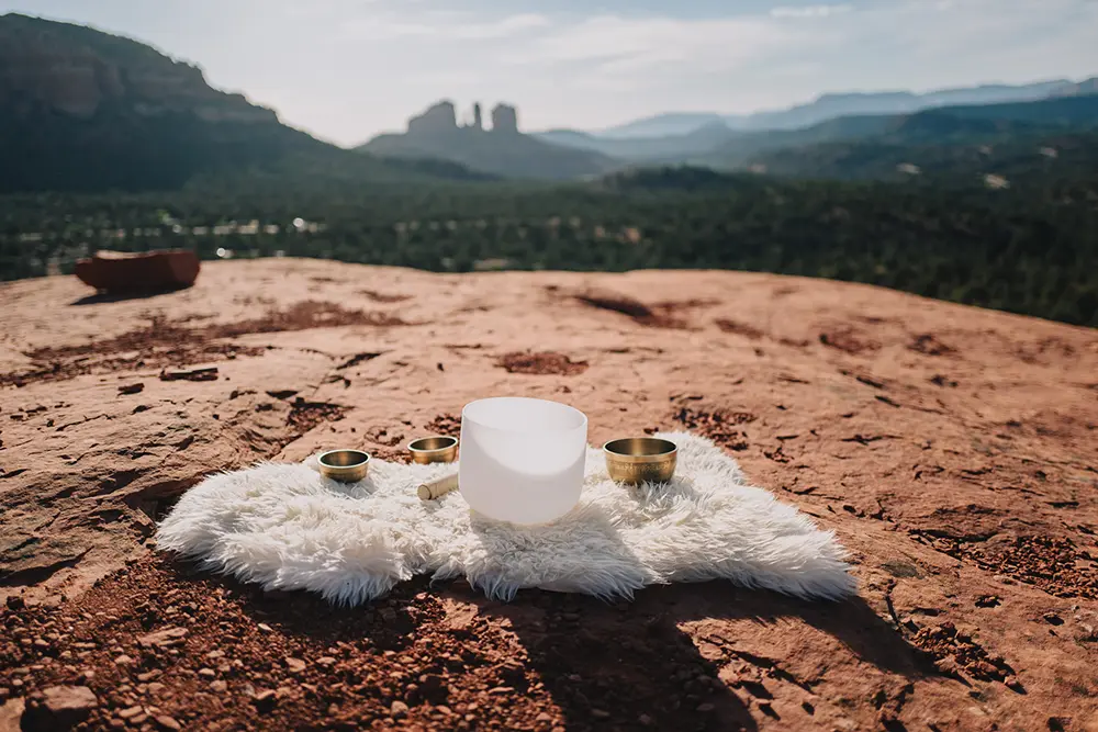 Crystal singing bowls placed on the red rocks of a Sedona vortex during a SpiritQuest sound healing session.
