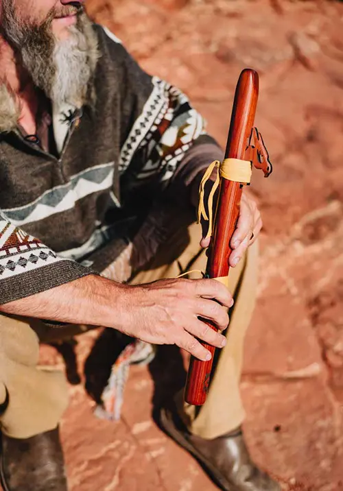 A practitioner playing a traditional wooden flute during a SpiritQuest Sedona red rock retreat ceremony.