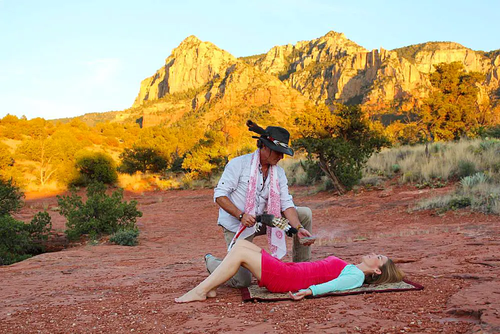 A private outdoor healing session taking place on the red rocks of a Sedona vortex site, featuring a practitioner and a guest.