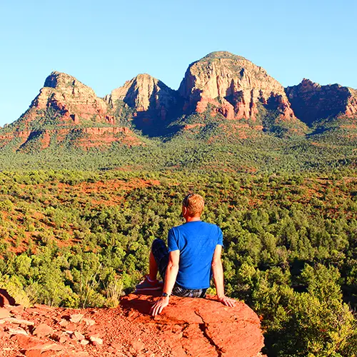 mens-retreat-spiritquest-sedona-red-rocks Participant enjoying a scenic meditation break overlooking Sedona's red rock formations during a SpiritQuest men's retreat